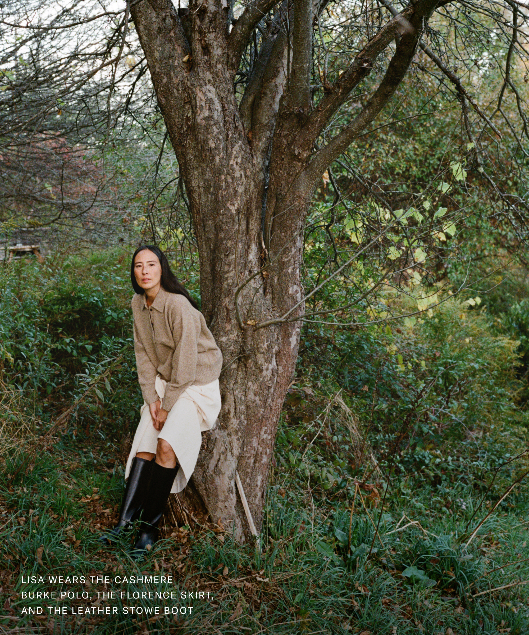 A woman gets down to brass tacks as she leans thoughtfully against a tree.